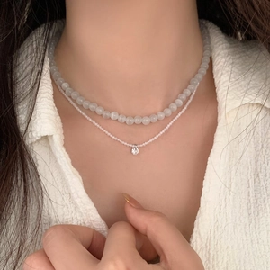 Détail du collier à deux rangs avec perles blanc laiteux et pendentif en zircon