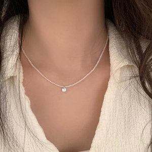Détail d'un collier de perles translucides avec un pendentif rond en cristal brillant