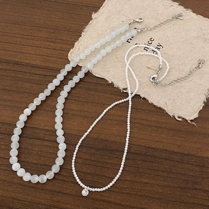 Détail de perles blanches mates et d'un collier de perles fines avec pendentif diamant