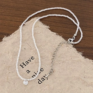 Détail du collier de perles facettées avec un pendentif solitaire en zircon brillant