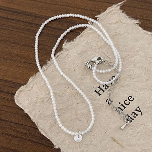Détail d'un collier de perles minimaliste avec pendentif en zircon sur bois
