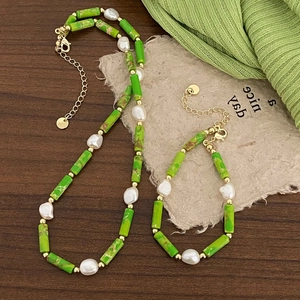 Detail view of green stones and baroque pearl necklace set on a vintage background