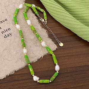 Close-up of green stone beads and baroque freshwater pearls necklace on wooden surface