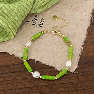 Detail of green stone beads and baroque pearls on a gold-plated link necklace