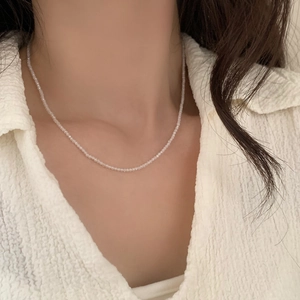 Detailed close-up of double-layer beaded necklace with white tiny beads on neck