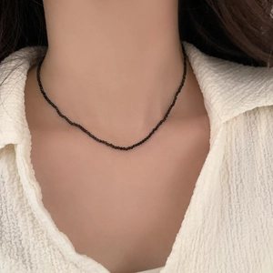 Detail of double-layer beaded necklace featuring faceted black micro beads and zircon charm