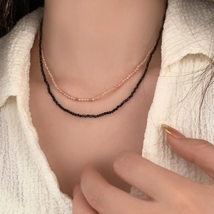 Close-up of double-layer beaded choker with minimalist black and nude faceted beads