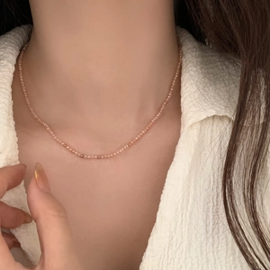 Detail of beaded choker necklace featuring delicate pink faceted beads worn on a model collarbone