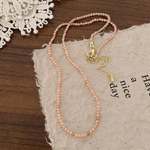 Detail of double-layer beaded necklace with pink stone beads and gold lobster clasp