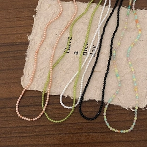 Detail of colorful double-layered beaded necklaces with micro-cut beads on textured paper