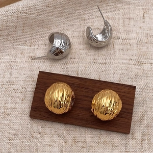 Detail of gold ball studs and silver C-shaped hoops with hammered metal texture
