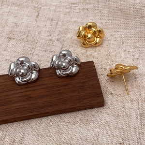 Elegant camellia petal stud earrings in polished gold and silver finish on wood