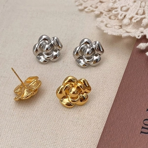 Detailed macro view of layered camellia petal earrings in polished gold and silver finishes