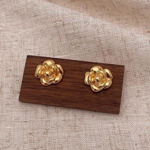 Macro shot of gold camellia flower stud earrings with layered metallic petals