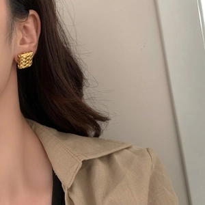 Vue détaillée de boucles d'oreilles carrées dorées avec texture tressée chic