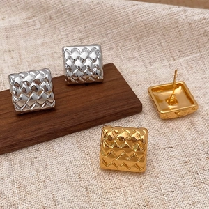 Vue macro de boucles d'oreilles carrées tressées en finitions or et argent sur tissu