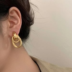 Boucles d'oreilles dorées minimalistes à double anneau géométrique sur un modèle élégant