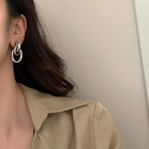 Vue détaillée de boucles d'oreilles anneaux doubles entrelacés en argent sur modèle