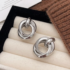 Close-up of silver multilayer twist earrings on a beige velvet jewelry display box
