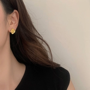 Close-up of model wearing gold camellia flower earrings with matte layered petals