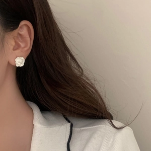 Close-up of a white camellia flower stud earring on model with matte finish