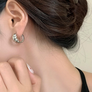 Minimalist silver croissant hoop earrings for women showing polished twisted metal texture