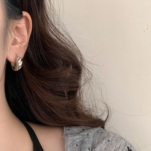 Close-up of silver twisted rope hoop earring worn by a model for a minimalist look