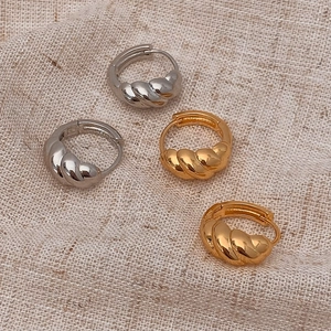 Close-up of croissant style twisted hoop earrings in gold and silver finish on fabric