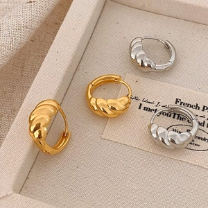 Minimalist croissant-style hoop earrings in polished gold and silver finishes on tray