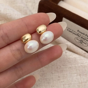 Gros plan de boucles d'oreilles perles et sphères dorées sur une boîte en bois