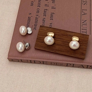 Gros plan de boucles d'oreilles perles vintage sur livres avec crochets dorés et argentés