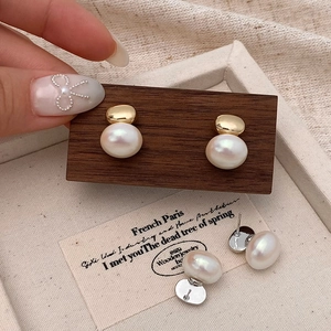 Boucles d'oreilles perles vintage françaises avec accents dorés sur un support en bois foncé