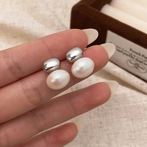 Gros plan de puces d'oreilles vintage en argent avec d'élégantes perles blanches ovales