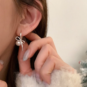 Close-up of elegant bow-knot pearl earrings with silver finish worn by a model