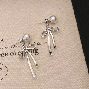 Gros plan de boucles d'oreilles nœuds argentées avec perles sur présentoir