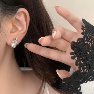 Gros plan de boucles d'oreilles nœud en perles et zircon porté par un mannequin