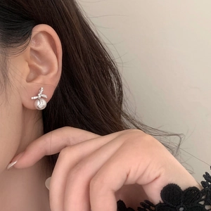 Gros plan de boucles d'oreilles nœud en perles et zircons portées par un mannequin