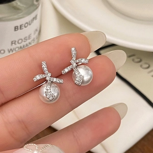 Vue macro de boucles d'oreilles nœud en argent avec zircons et perles blanches élégantes