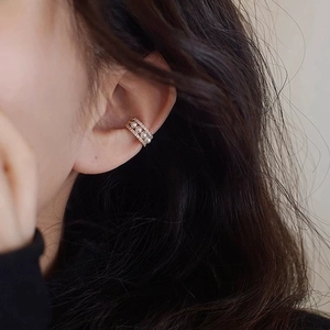 Detailed close-up of a gold-plated pearl ear cuff with tiny crystals on a model's ear