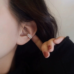 Close-up of golden ear cuff with three white pearls and sparkling zircon accents