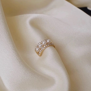French retro gold ring with four linear pearls and diamond accents on silk background