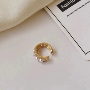 Detailed close-up of a double-layered gold ear cuff with pearls and crystal inlay