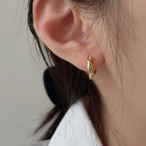Close-up of golden twisted rope hoop earrings showcasing polished metallic texture