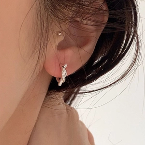Detail of silver twisted knot hoop earring worn by a model in a natural setting