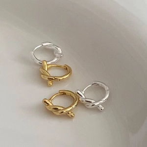 Close-up of knot design gold and silver hoop earrings in a ceramic jewelry tray