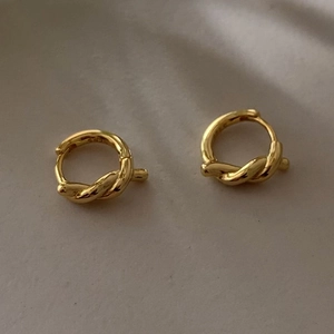Close-up of golden knotted rope hoop earrings with S925 hallmark on inner band