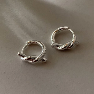 Macro detail of silver S925 knotted rope hoop earrings with a polished metallic finish