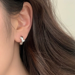 Close-up of minimalist silver hoop earring with three sparkling zircons on a model