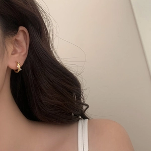 Close-up of minimalist golden C-shaped hoop earrings with zircon stones on model