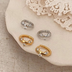 Detail of silver and gold hoop earrings with sparkling cubic zirconia on fabric